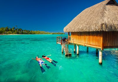 Young couple snorkling from hut over blue tropical lagoon