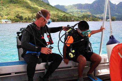 Scuba instructor and kid taking a lesson, preparing to jump off the boat